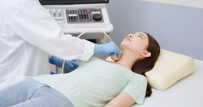 Ein Arzt führt eine Ultraschalluntersuchung der Schilddrüse bei einer jungen Frau mit Verdacht auf Schilddrüsenkrebs durch